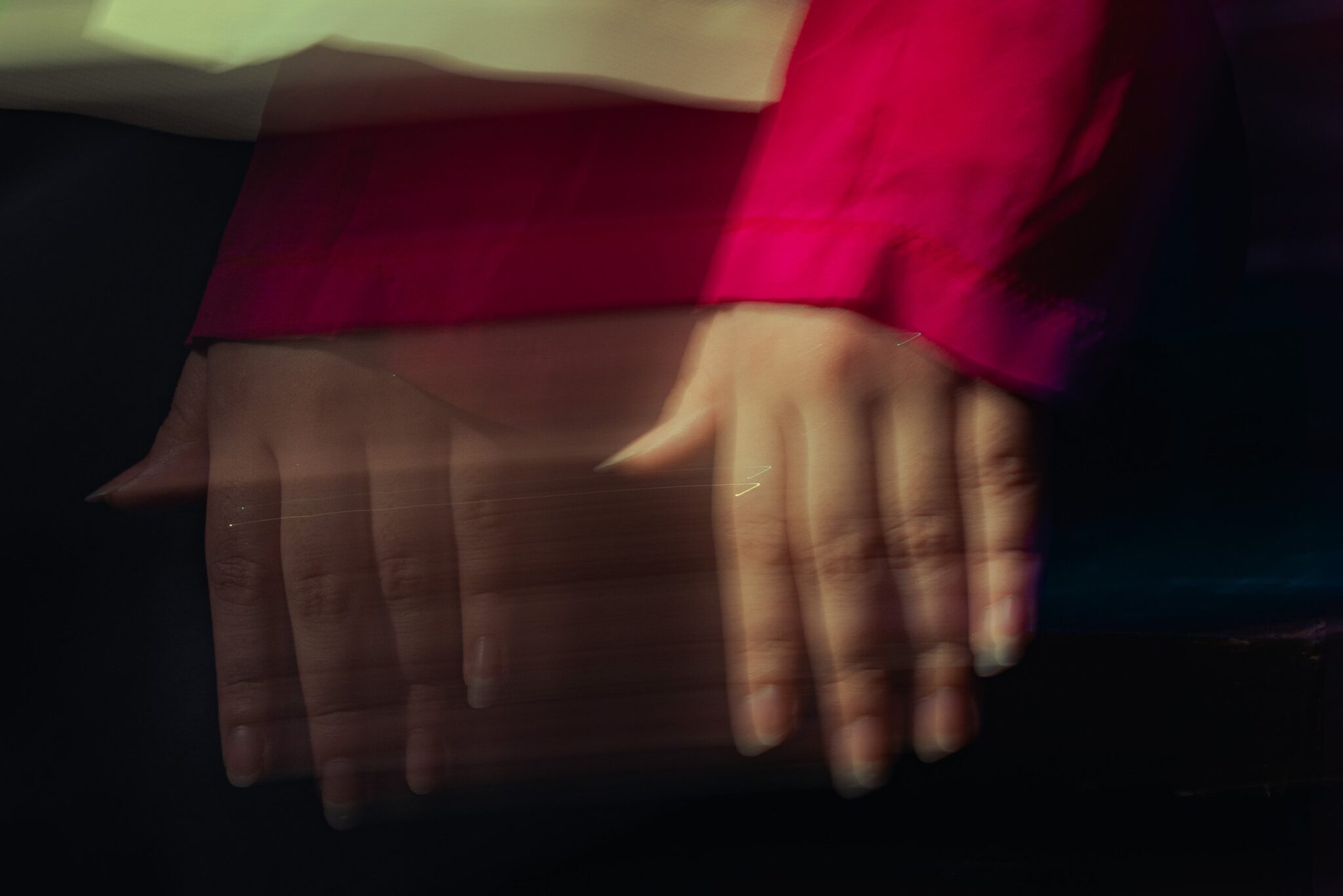 Motion-blurred hands of a performer beneath a red silk sleeve