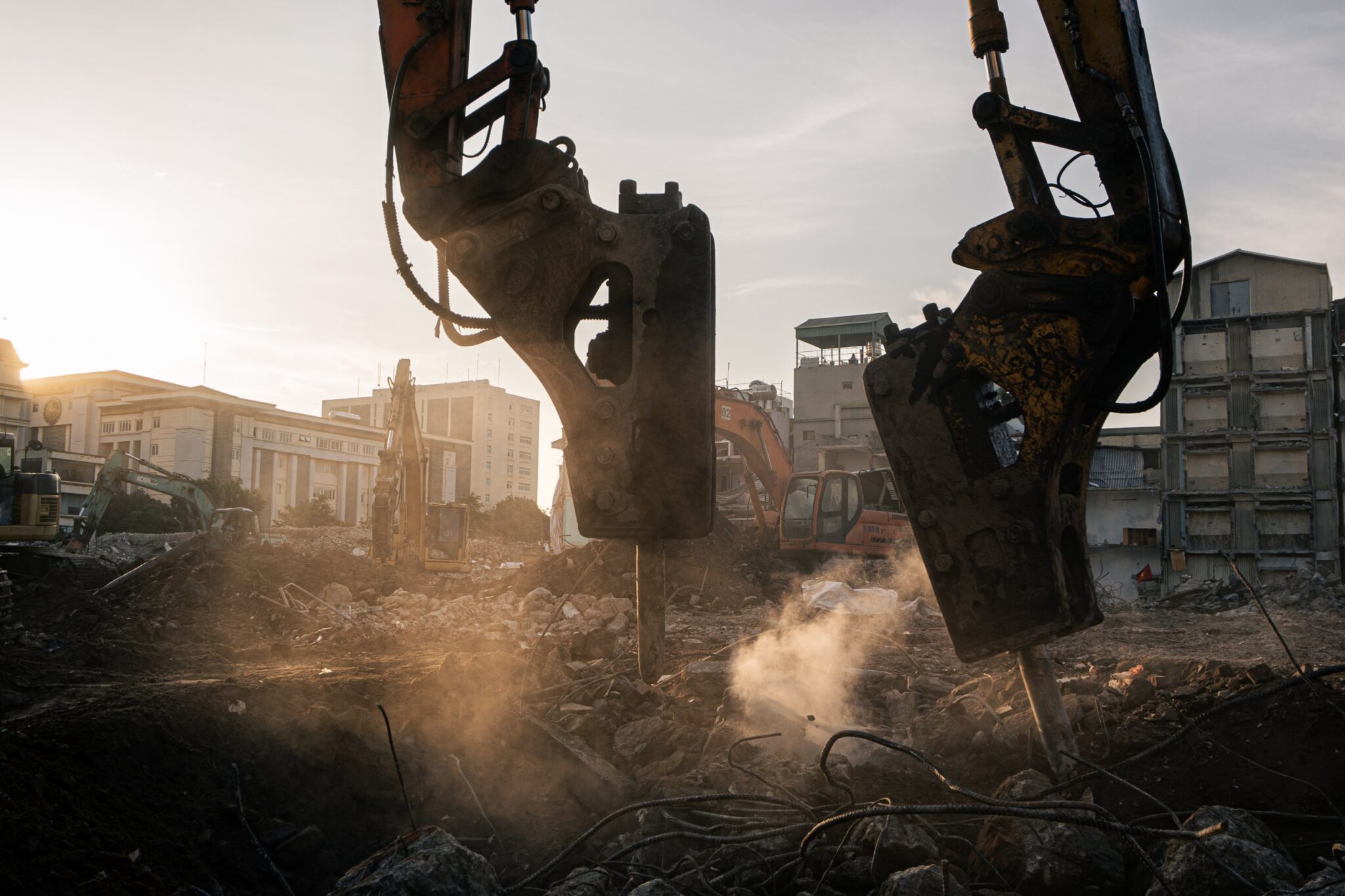 Hydraulic breakers striking rubble at sunset