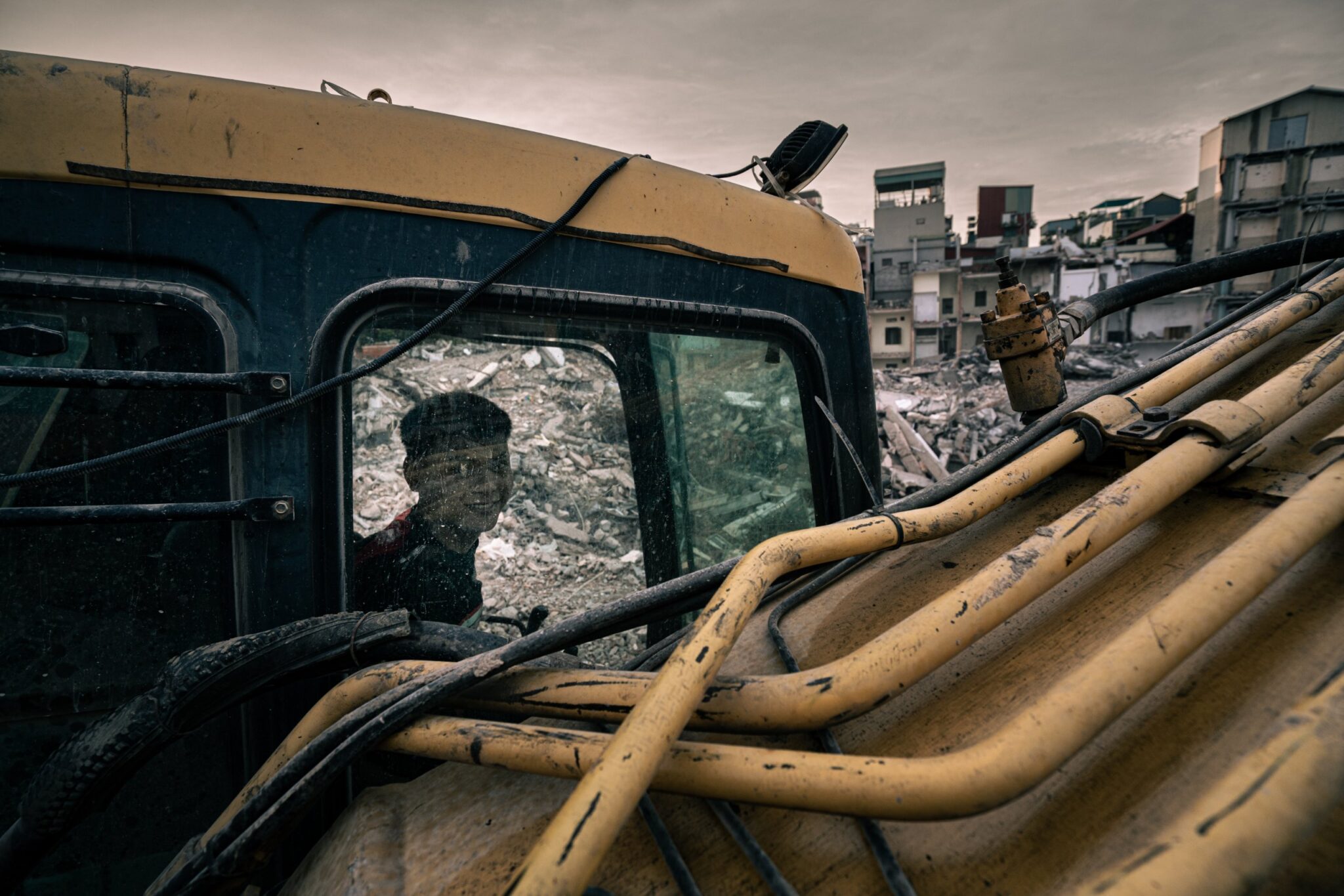 Boy peering through the window of an excavator cab