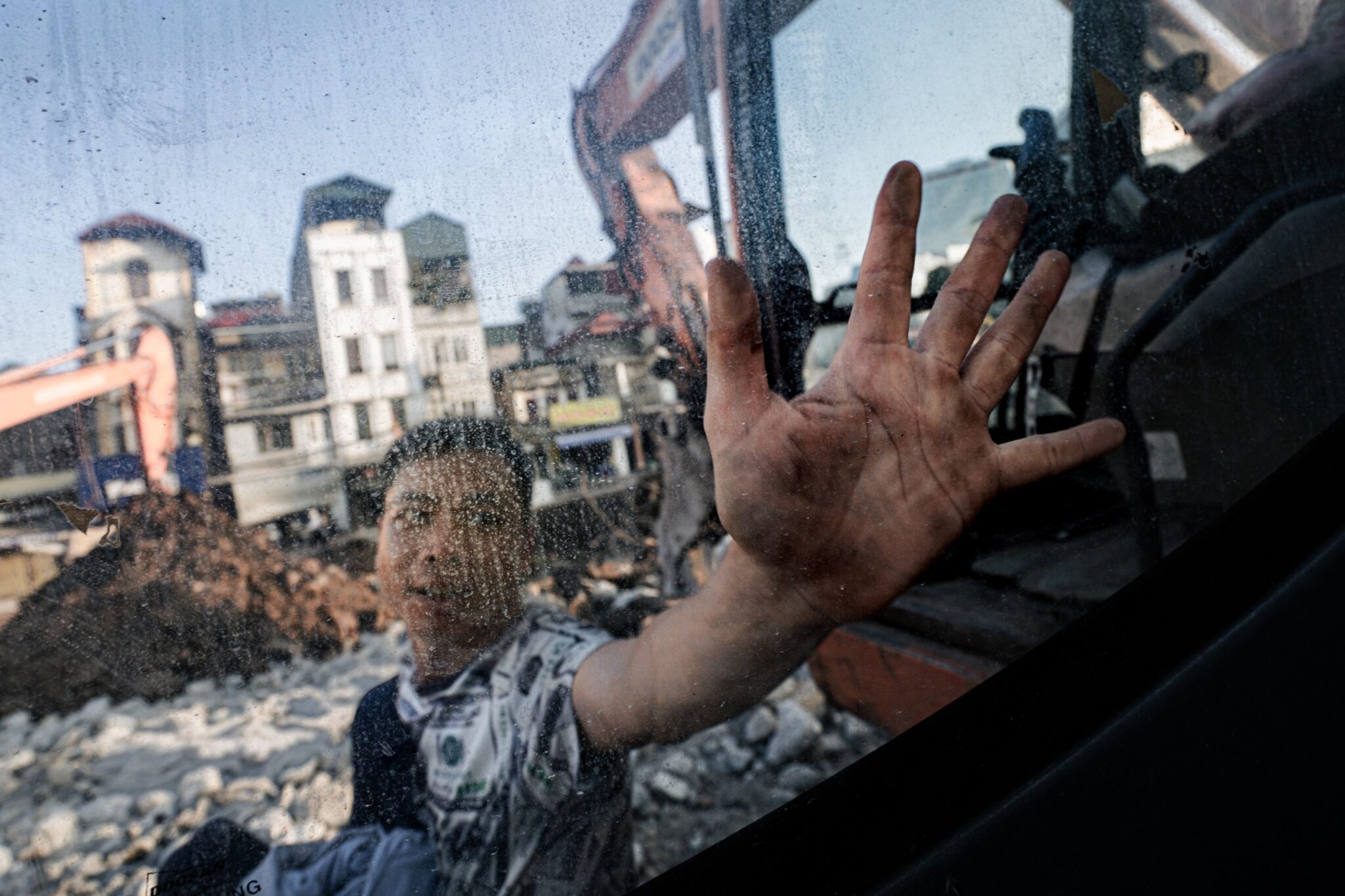 Man pressing his hand against a dusty excavator window