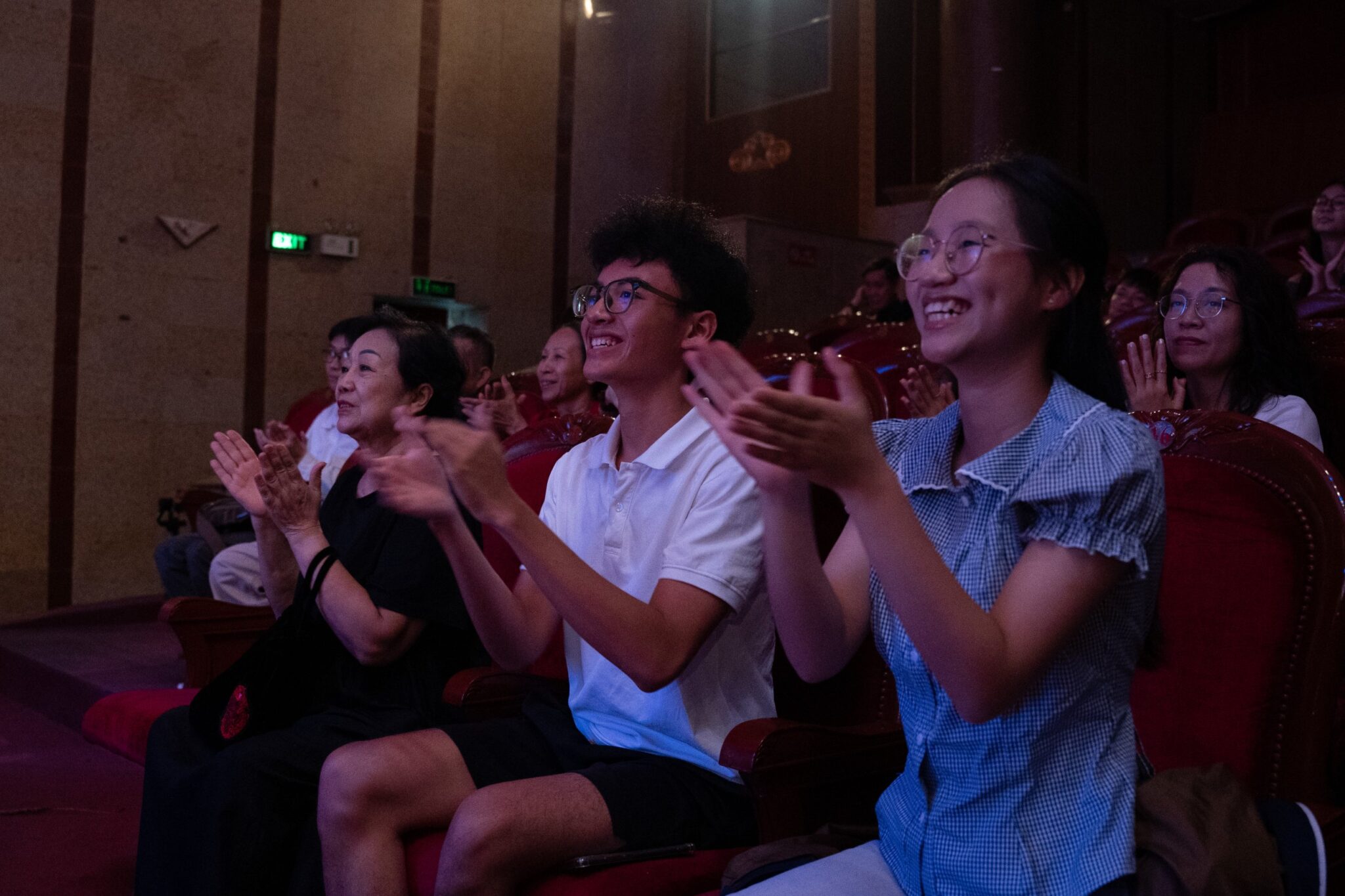 Audience members smiling and applauding in the theatre