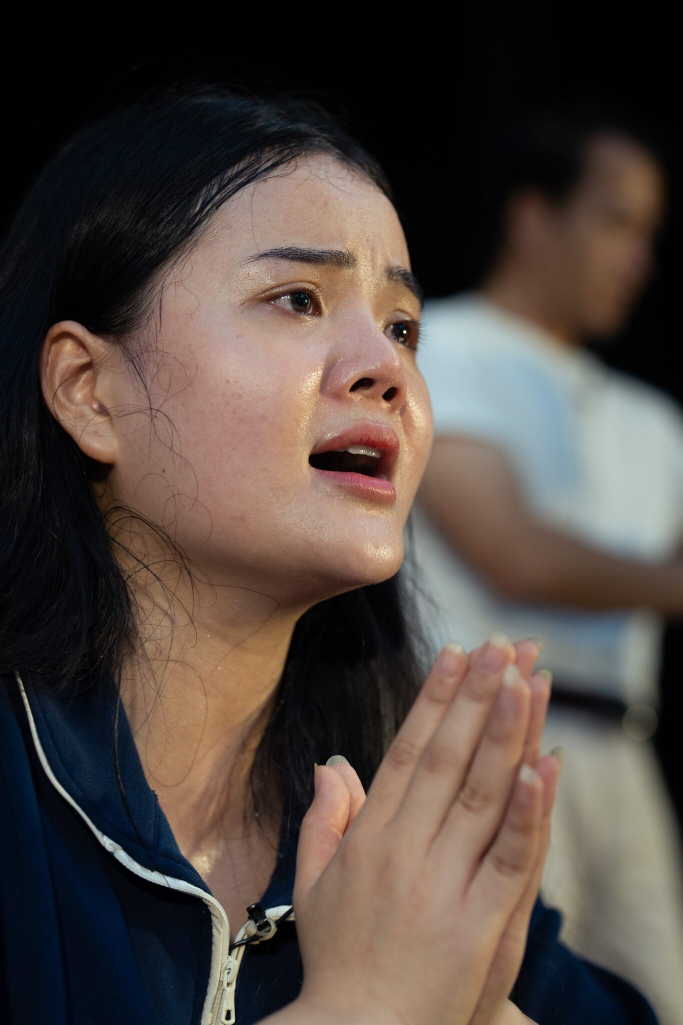 Actress in tears with hands pressed together during rehearsal