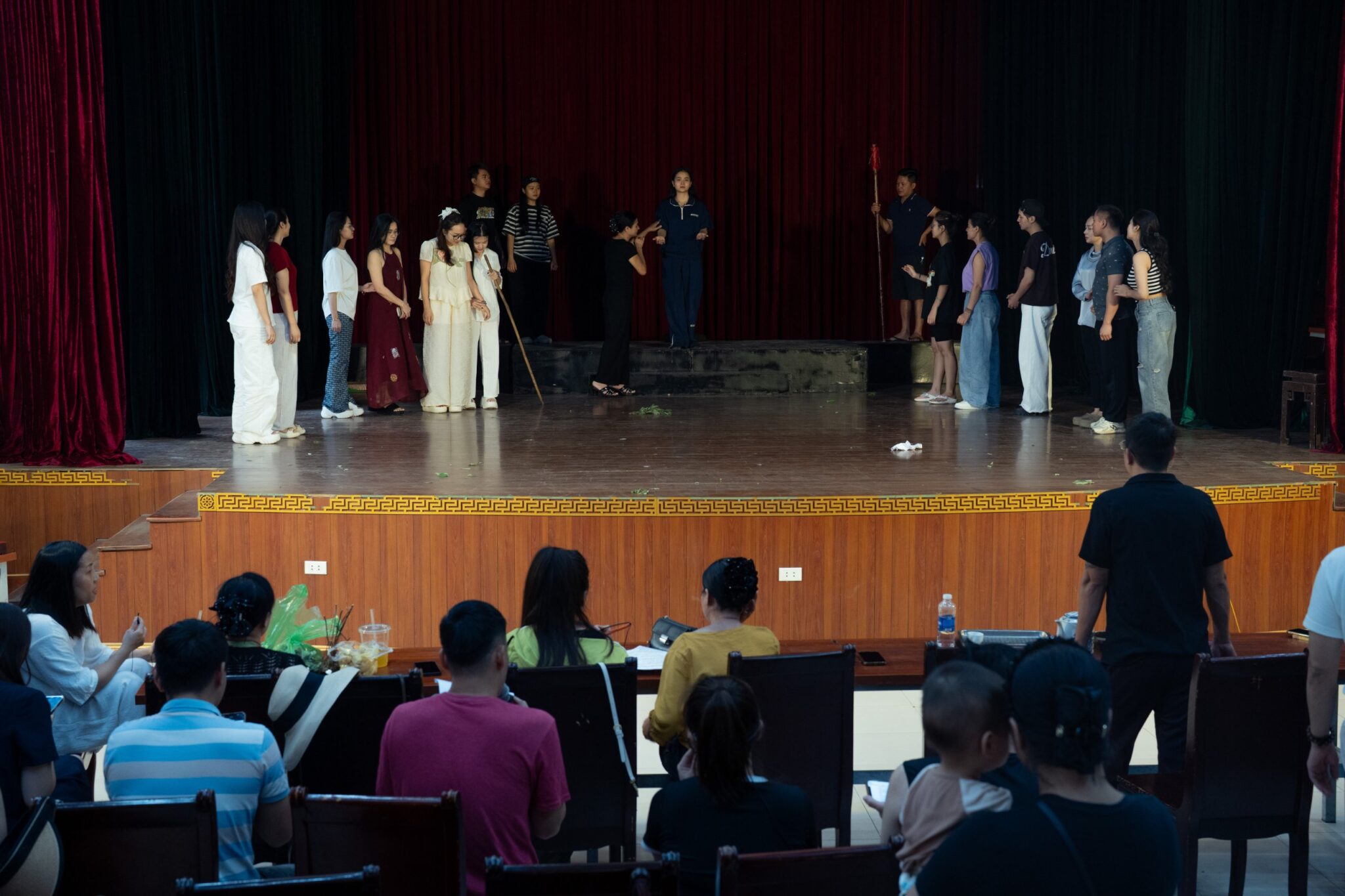 Wide view of a rehearsal on stage, watched from the seats in front